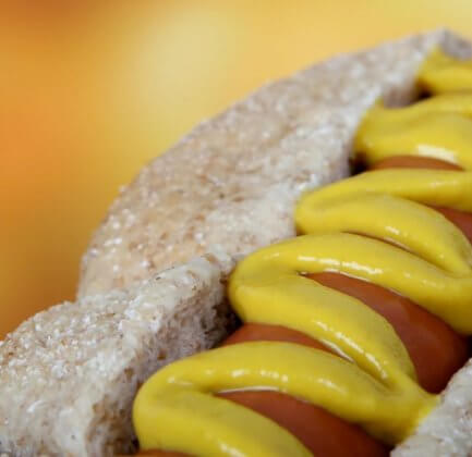 a hotdog with mustard on it in close up